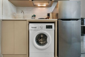 A compact kitchen with a built-in washer and refrigerator. - Narela by Kozystay - Kemayoran (Central Jakarta)