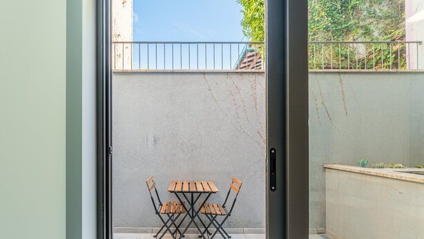 Un patio con tavolo e sedie, un cancello in metallo e un muro in cemento.