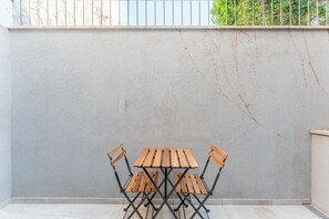 A patio with a table and chairs, a concrete floor, and a grey wall with some vines. - GuestReady - Cosy place in Braga's historic heart (Braga)