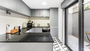 Una cucina moderna con un piano di lavoro nero, elettrodomestici in acciaio inossidabile e un backsplash piastrellato bianco.