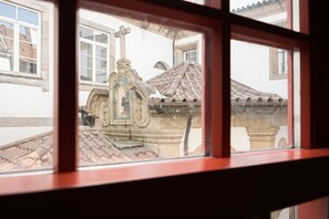 Blick aus dem Fenster auf ein Gebäude mit einer Steinstruktur, einem Kreuz und einem Ziegeldach.