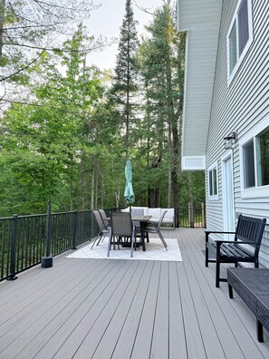 A deck with a table and chairs, a bench, and a railing.
