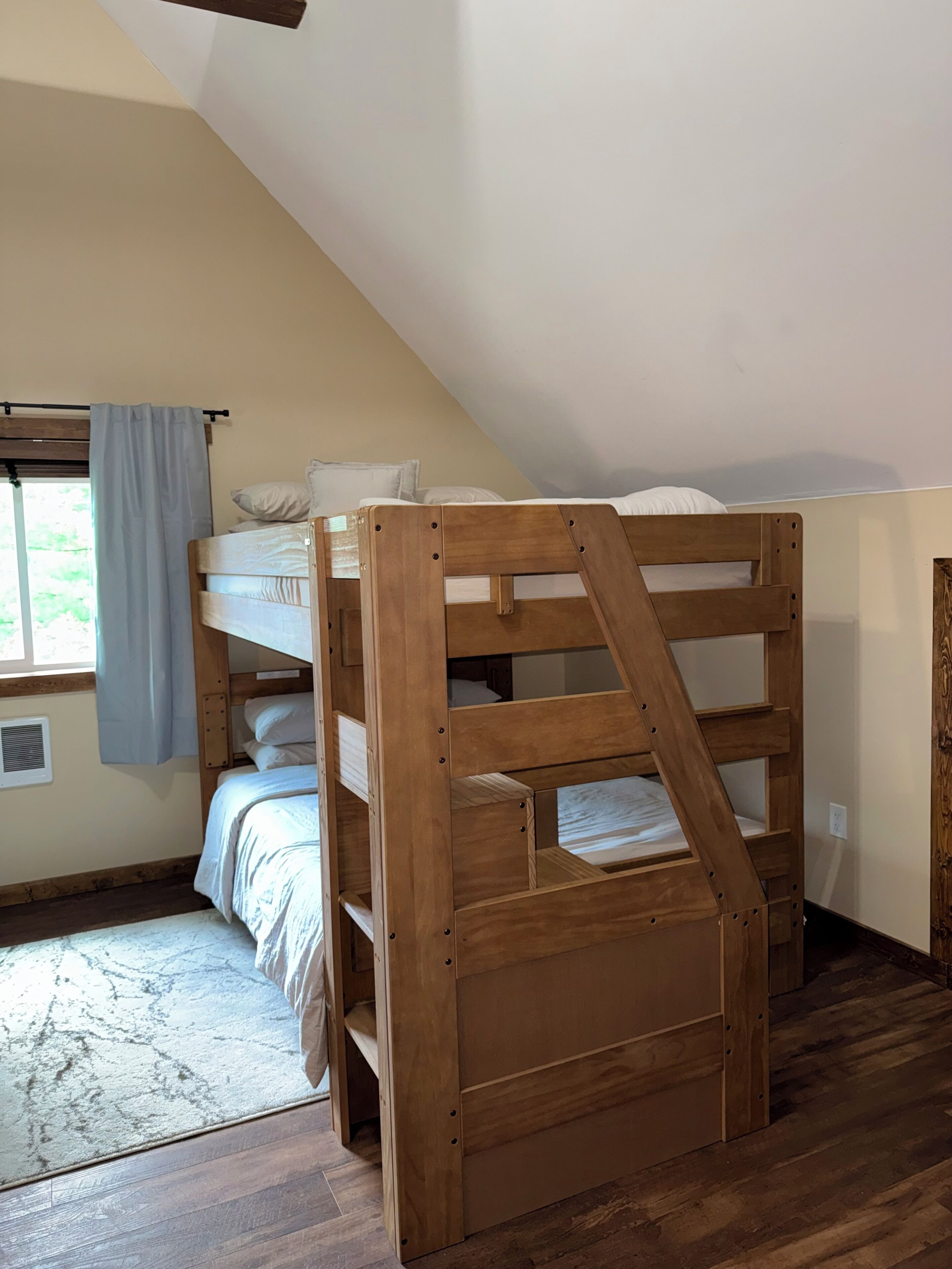 A bunk bed with a wooden frame in a room with a sloped ceiling.