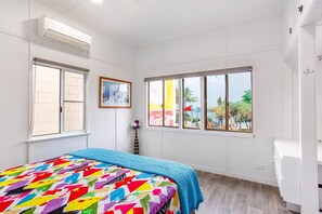 A bedroom with a bed, a window, an air conditioning unit, and a view of the outside. - Wake to Sunrises on Yeppoon’s Beachfront (Yeppoon)
