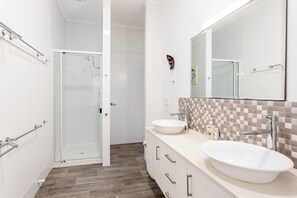 A modern bathroom with two sinks, a glass shower enclosure, and a checkered tile backsplash. - Wake to Sunrises on Yeppoon’s Beachfront (Yeppoon)
