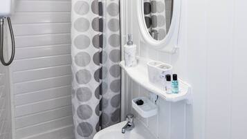 A bathroom with a shower, toilet, sink, and a mirror.