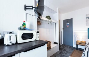 Eine kleine Küchenzeile mit Mikrowelle, Toaster und einer hängenden Pflanze.