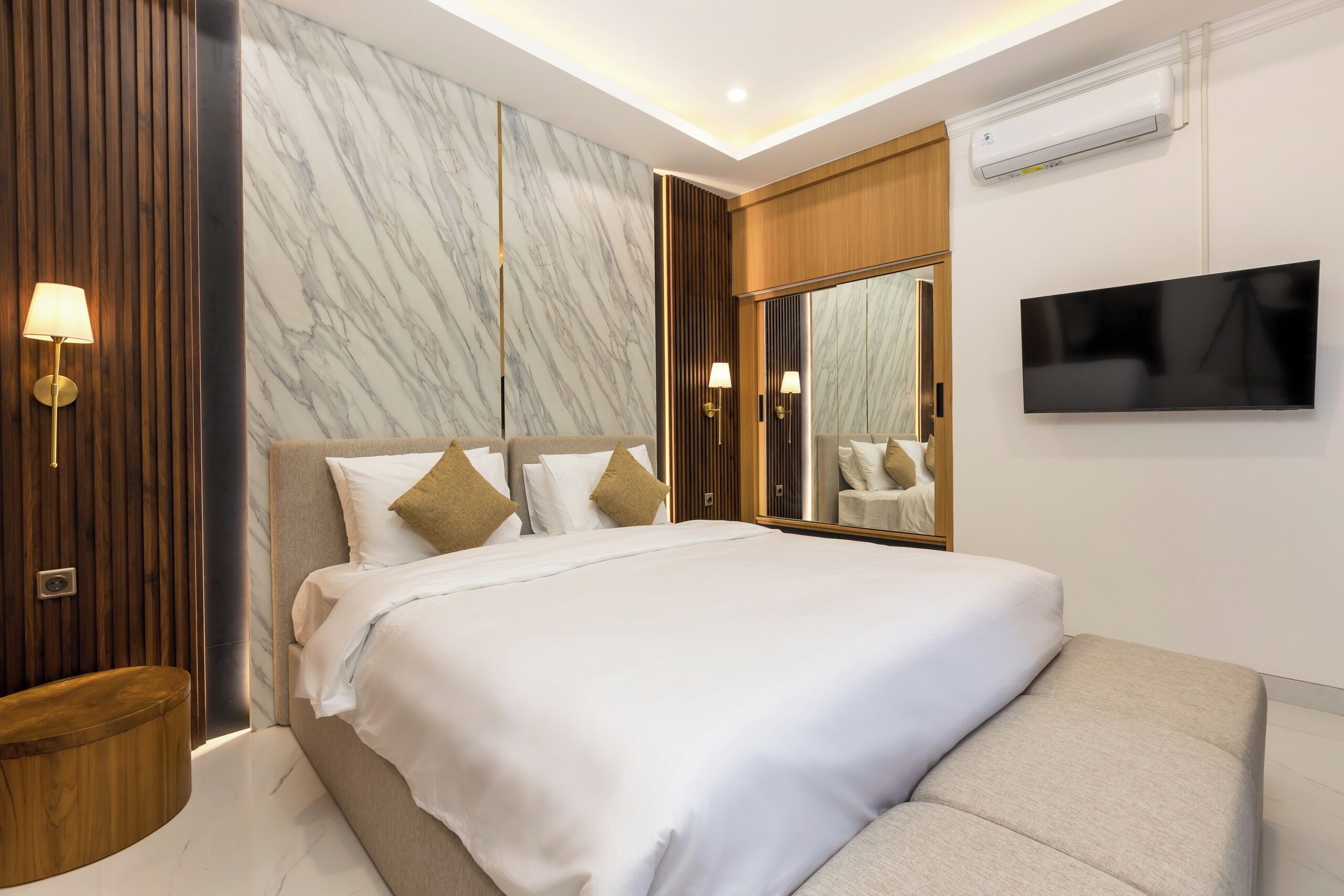 Een moderne hotelkamer met een groot bed, een flatscreen televisie, een marmeren wand en een houten accentwand.