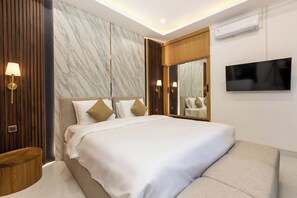 Ein modernes Hotelzimmer mit einem großen Bett, einem Flachbildfernseher, einer Marmorwand und einer Holzvertäfelung.