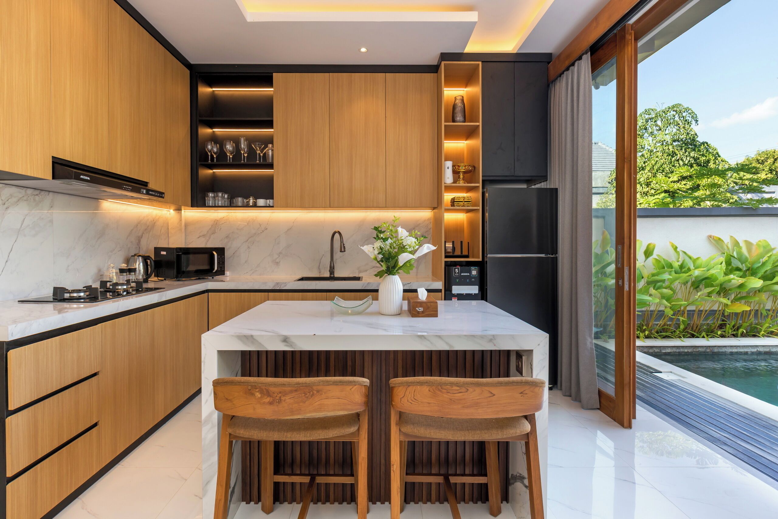 A modern kitchen with a marble countertop, wooden cabinets, and a built-in wine rack.