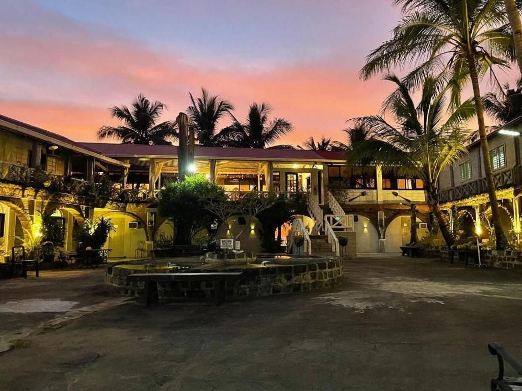 Un patio con una fuente, palmeras y un edificio de techo rojo.