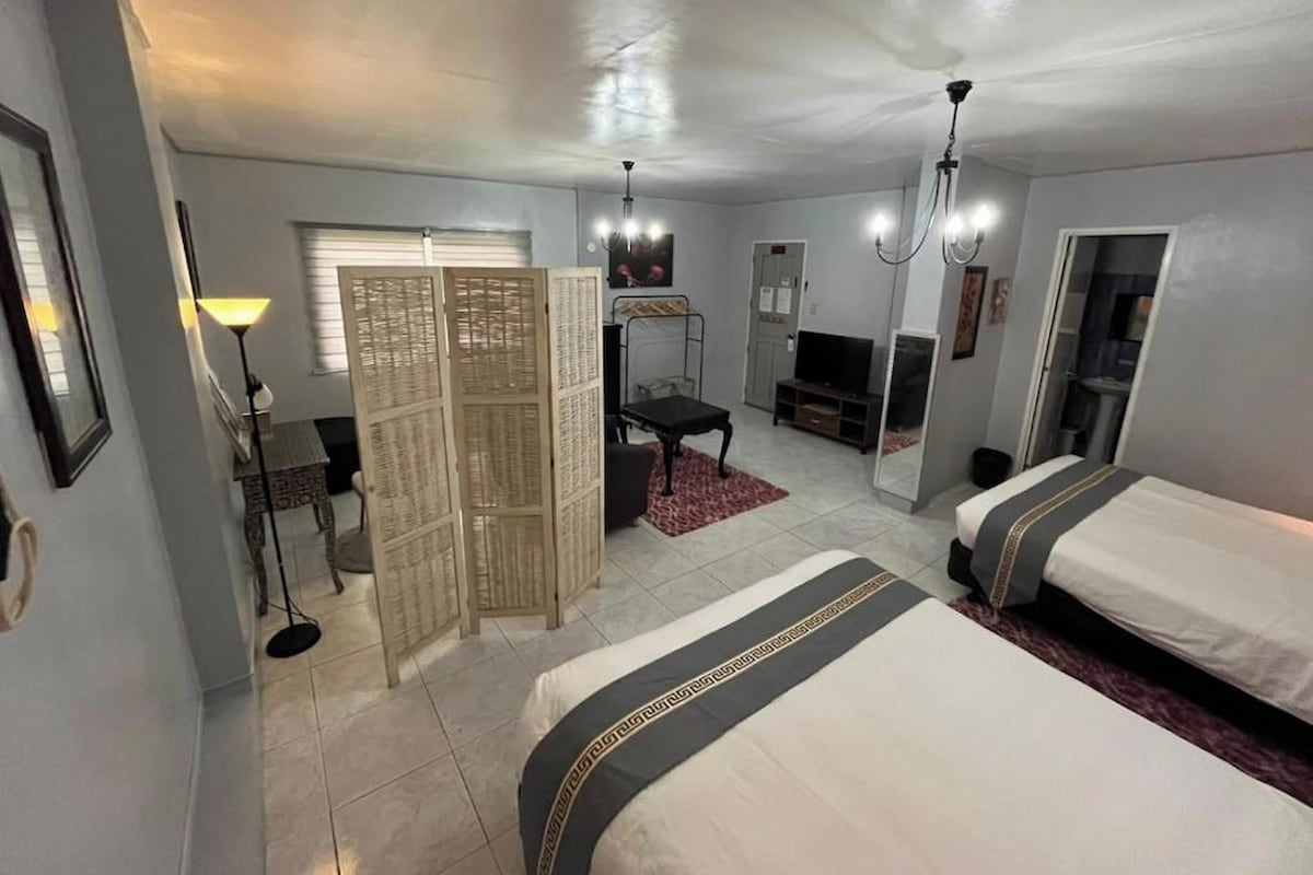 A hotel room with two beds, a desk, a chair, a television, and a wardrobe.