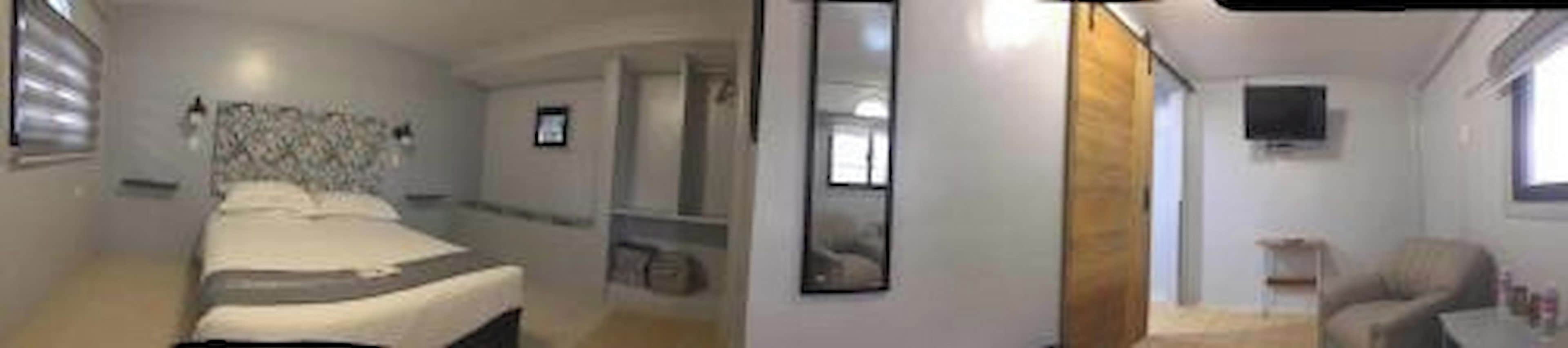 Une chambre d’hôtel avec un lit, une télévision et une fenêtre.