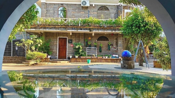 A stone building with a wooden door, a small garden, and a water feature in front. - Sunbloom Beach Resort (Candelaria)