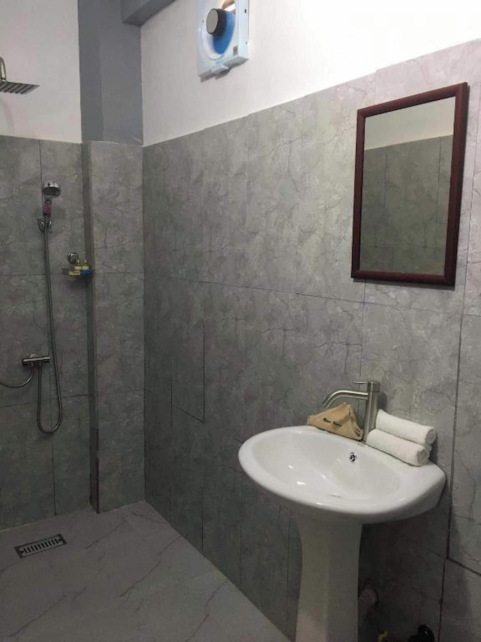 Un baño con ducha, lavabo y espejo.
