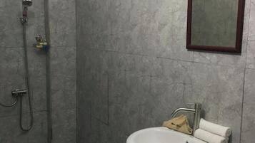 Un baño con ducha, lavabo y espejo.