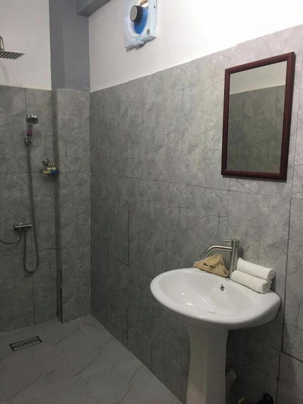 A bathroom with a shower, a sink, and a mirror.