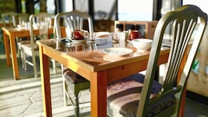 A dining area with wooden tables and chairs, some with cushions. - Sunbloom Beach Resort (Candelaria)