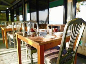 A dining area with wooden tables and chairs, some with cushions. - Sunbloom Beach Resort (Candelaria)