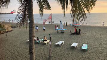 Una playa con palmeras, una bandera y gente.