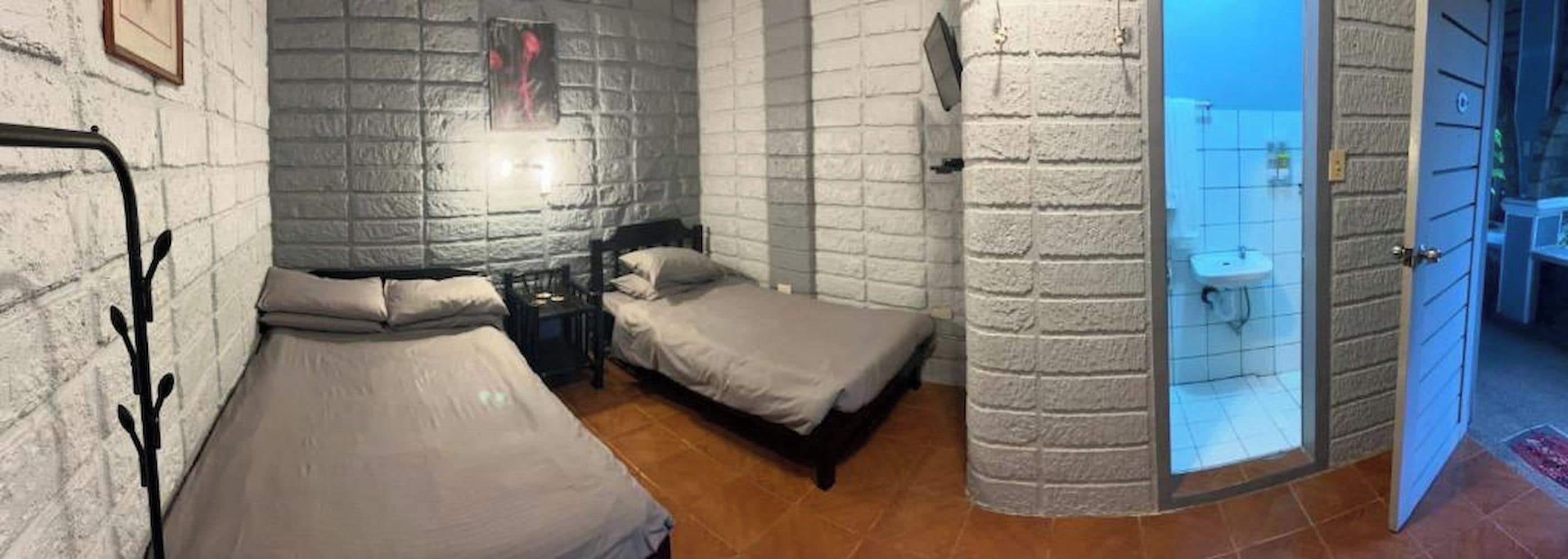 A room with two beds, a nightstand, and a bathroom visible through an open door.