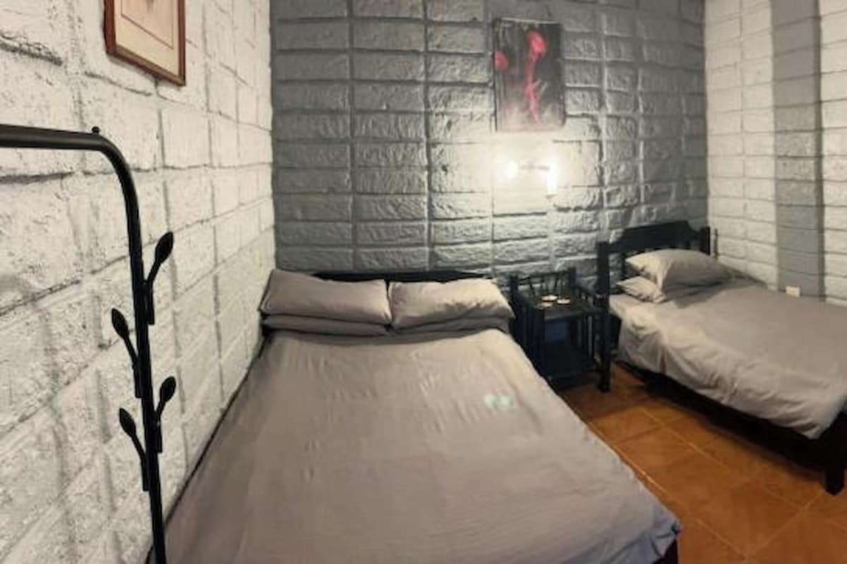 A room with two beds, a nightstand, and a bathroom visible through an open door.
