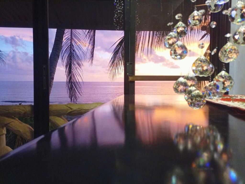 Una habitación con vista al océano, una mesa de madera y adornos de cristal colgantes.