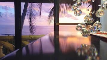 Une pièce avec vue sur l’océan, une table en bois et des décorations en cristal suspendues.