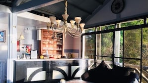 A cozy interior with a bar area, a chandelier, and a large window offering a view of trees. - Sunbloom Beach Resort (Candelaria)