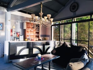 A cozy interior with a bar area, a chandelier, and a large window offering a view of trees. - Sunbloom Beach Resort (Candelaria)