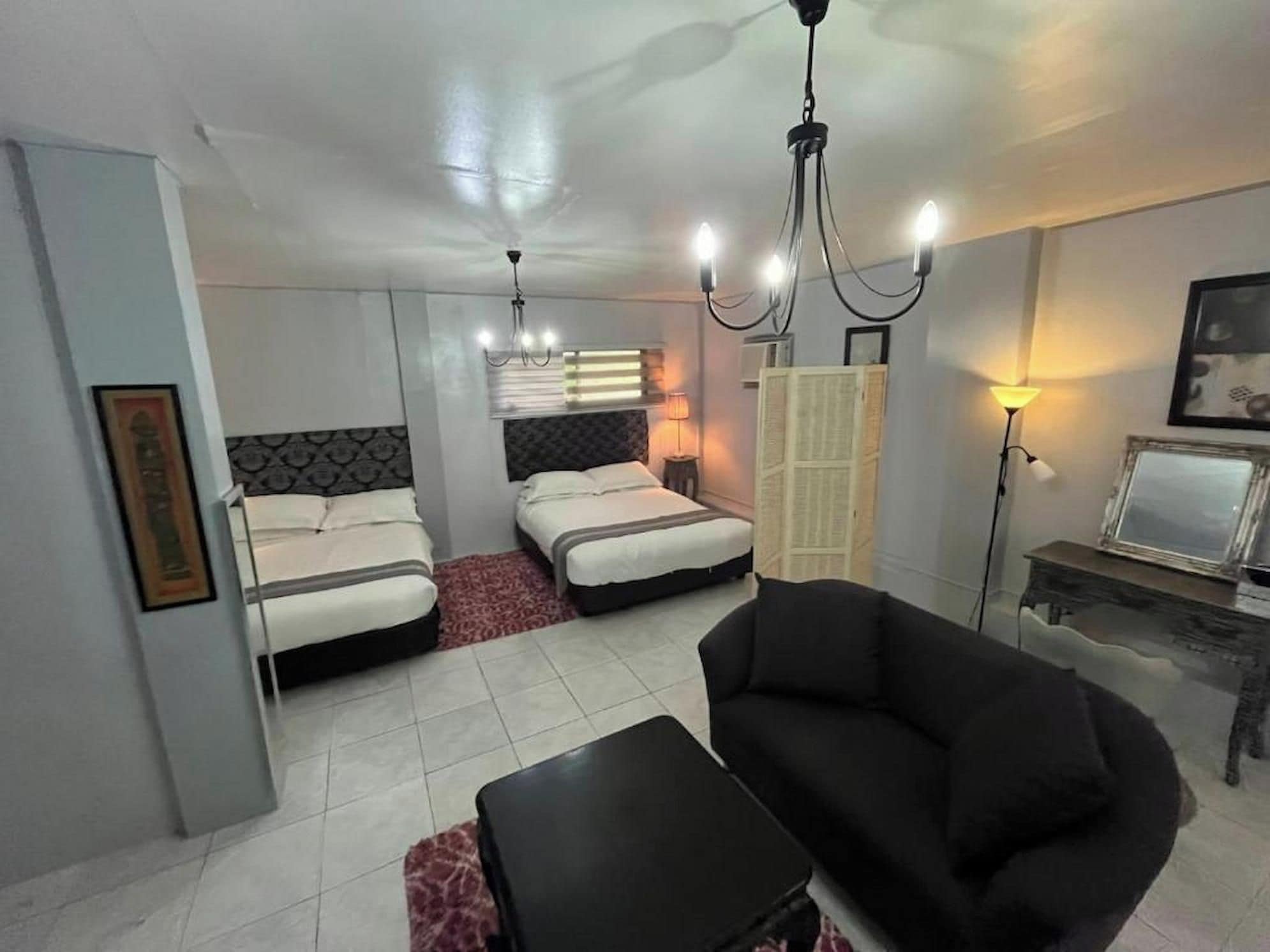 Habitación de hotel con dos camas, un sofá, una mesita y un televisor.