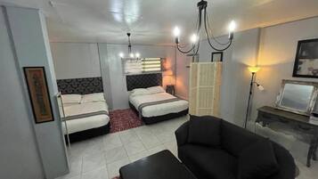 Habitación de hotel con dos camas, un sofá, una mesita y un televisor.