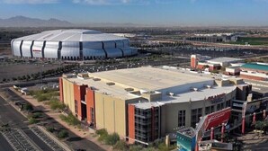 A large stadium with a distinctive dome structure, surrounded by commercial buildings and parking areas.