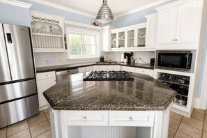 A kitchen with white cabinetry, a granite countertop, a stainless steel refrigerator, a gas stove, and a microwave. - Private Pool Retreat | 6BR 3.5 BA | BBQ & Firepit (Cobourg)