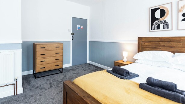 Ein Hotelzimmer mit einem Bett, einem Holzschrank, einem Nachttisch mit Lampe und einer Tür mit Schild.