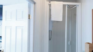 Ein Badezimmer mit Dusche, Waschbecken und einer weißen Tür.