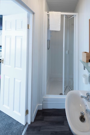 A bathroom with a shower, a sink, and a white door. - The Bay Apart-Hotel by Guestz (Morecambe)