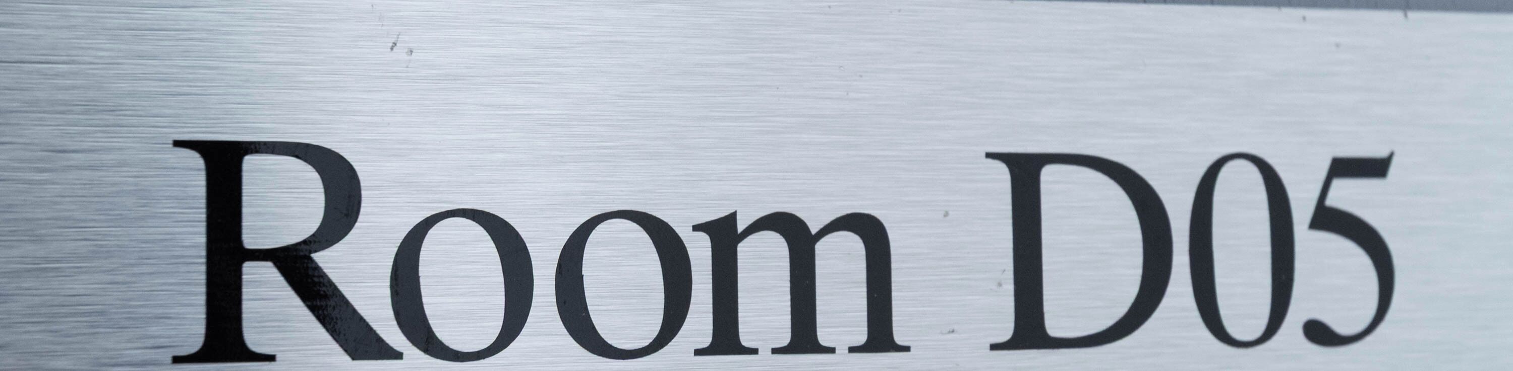 Un letrero con el texto 'Room D05' sobre una superficie metálica.