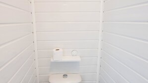 Ein kleines, weißes Badezimmer für eine Person mit Toilette, Bidet und Toilettenpapierhalter.