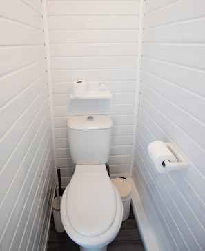 A small, white, single-occupancy bathroom with a toilet, a bidet, and a toilet paper holder. - The Bay Apart-Hotel by Guestz (Morecambe)