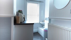 Ein Badezimmer mit Toilette, Waschbecken und einem Fenster mit Jalousien.