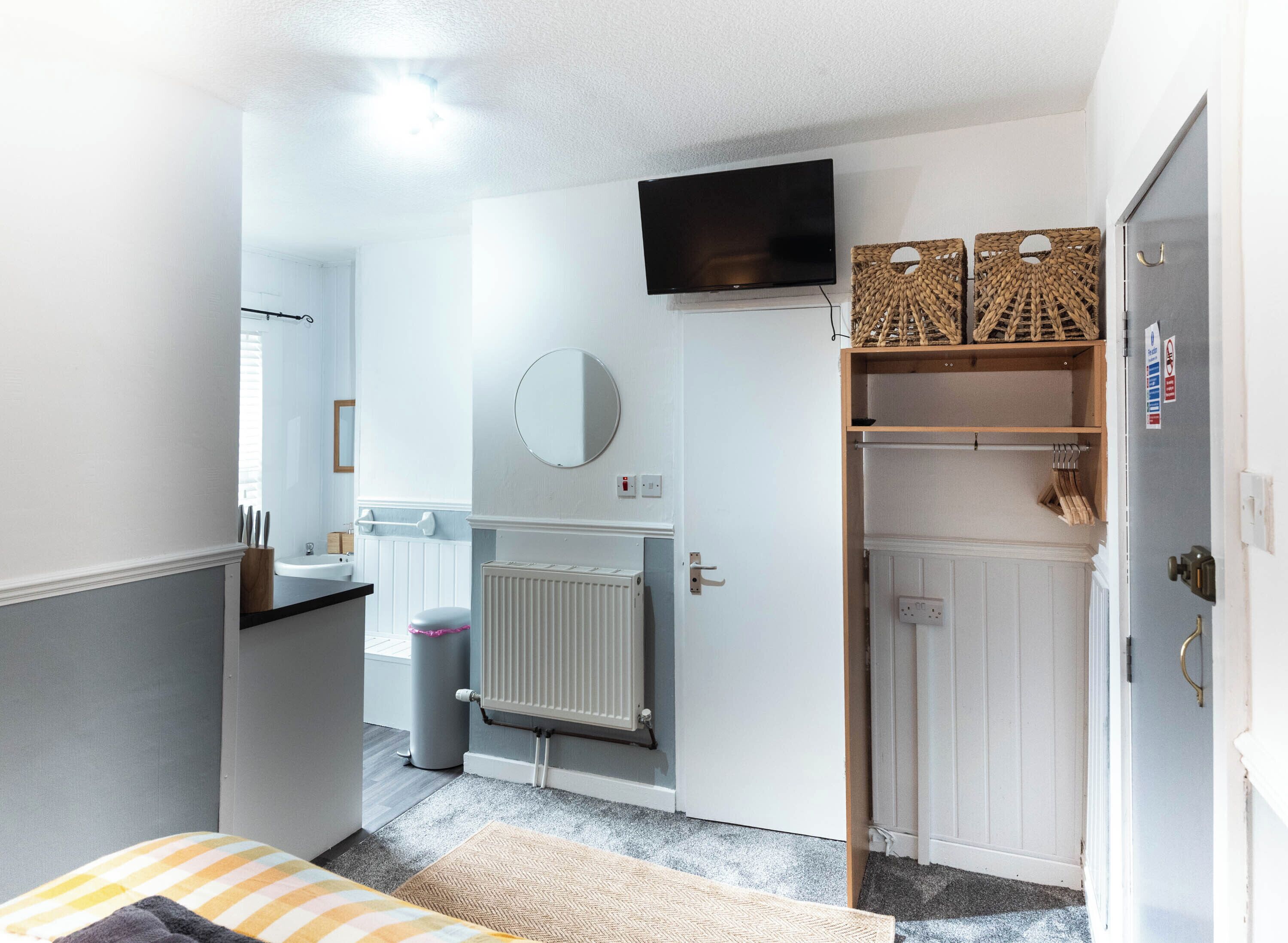 Una stanza compatta con un letto, un termosifone, una televisione e un armadio.