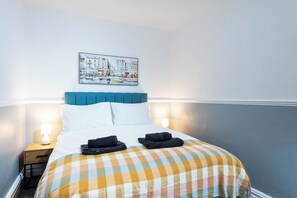 Une chambre d’hôtel avec un lit, une table de chevet, une lampe et un tableau accroché au mur.