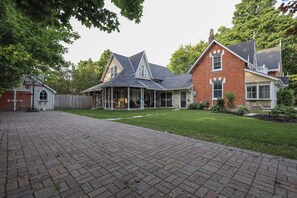 Une maison à deux étages, avec une façade en briques, un porche à l’avant et une pelouse bien entretenue.