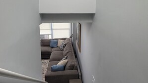 Eine Treppe führt zu einem Wohnbereich mit einer Couch und Kissen.