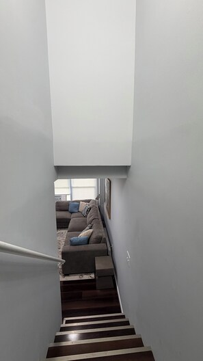 A staircase leading to a living area with a sofa and cushions. - Furnished Half-Duplex in Newark’s West Side - Gated, Secure & Move-In Ready (Newark)