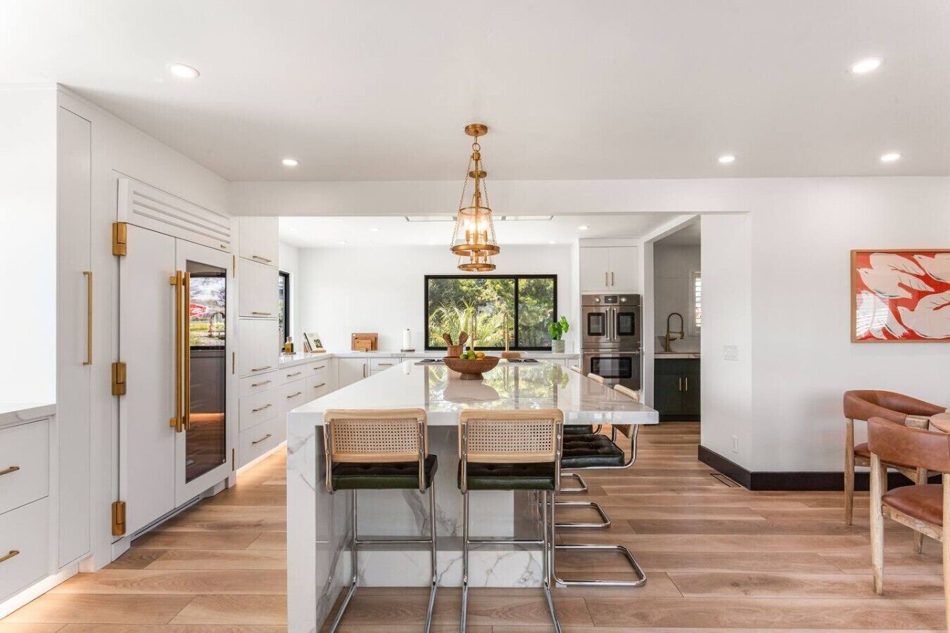 A modern kitchen with a central island, stainless steel appliances, and a large window.