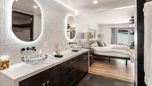 Un baño moderno con un espejo grande, un lavabo de vidrio y muebles oscuros.