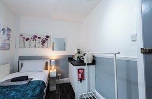 Une chambre d’hôtel avec un lit, une table de chevet, une lampe et une couverture anti-feu accrochée au mur.