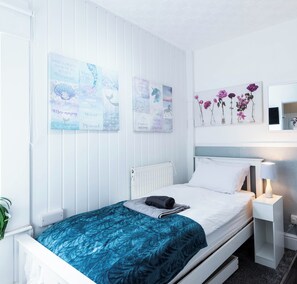 A bedroom with a bed, a nightstand, a lamp, and wall art. - The Bay Apart-Hotel by Guestz (Morecambe)